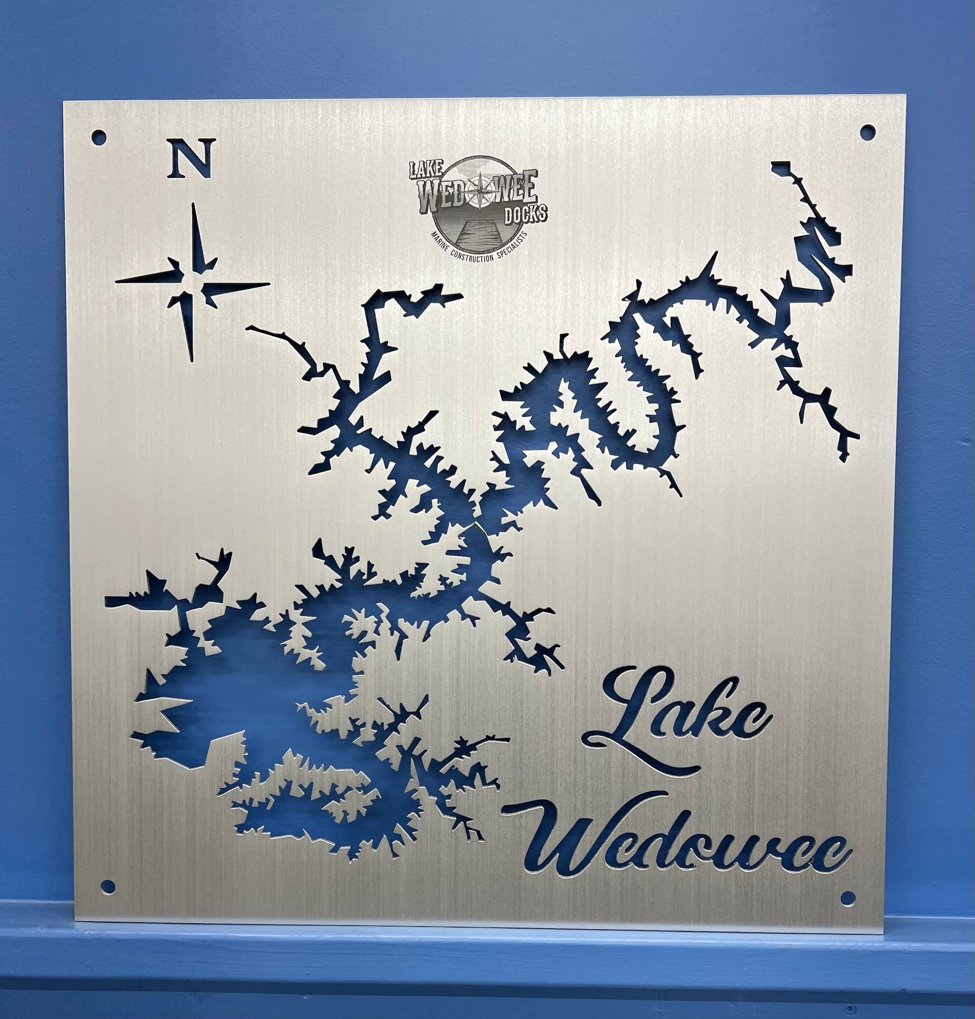 Lake Wedowee metal map with compass rose and "Lake Wedowee Docks" logo on brushed silver, mounted on a blue wall.