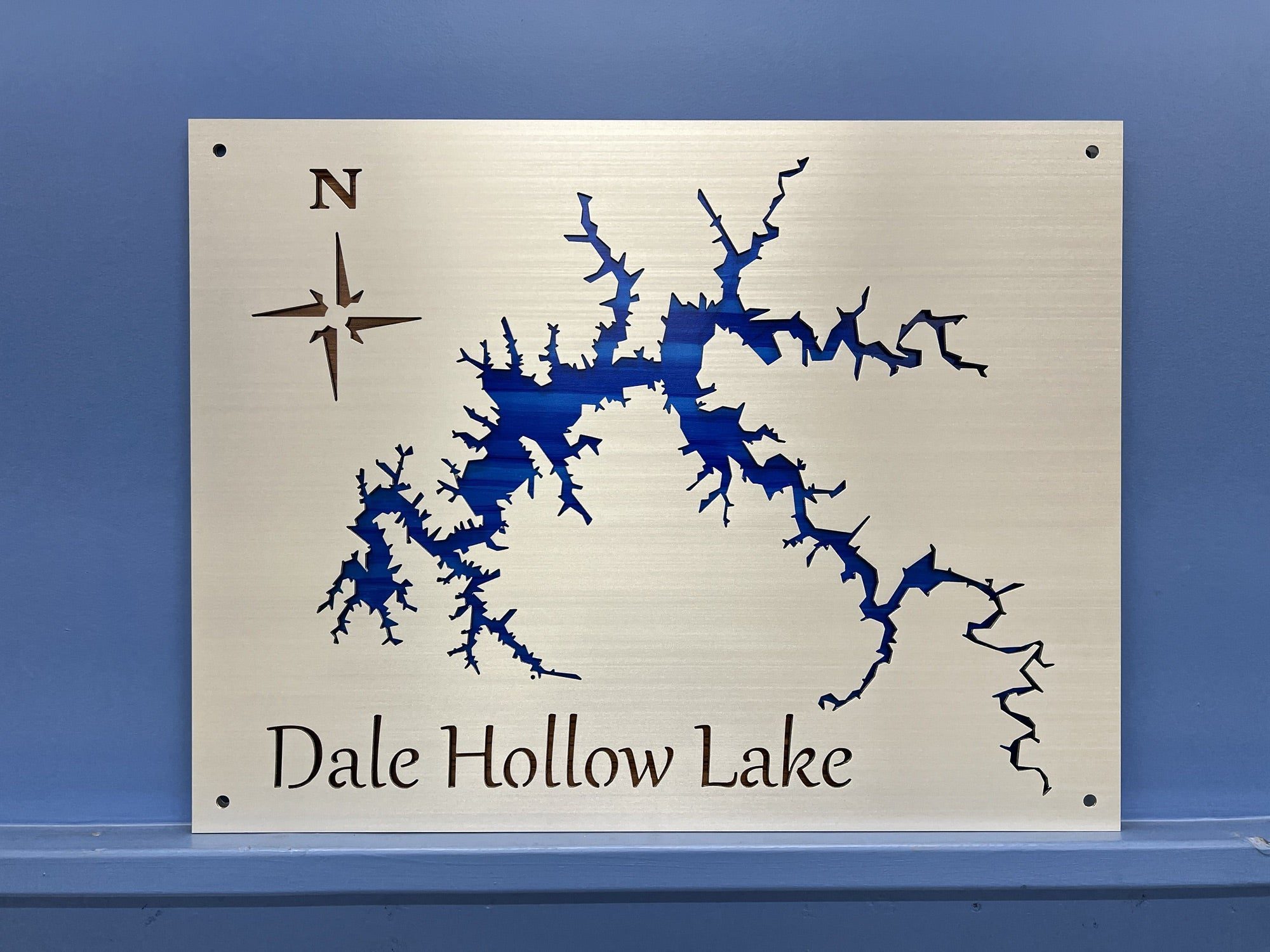 Custom metal map of Dale Hollow Lake with compass rose on a polished background, mounted on a blue wall.