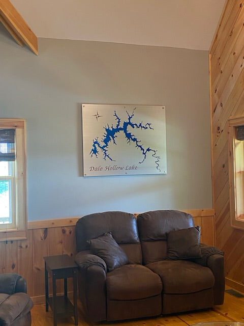 Metal map of Dale Hollow Lake with blue silhouette, mounted above a couch in a rustic living room.