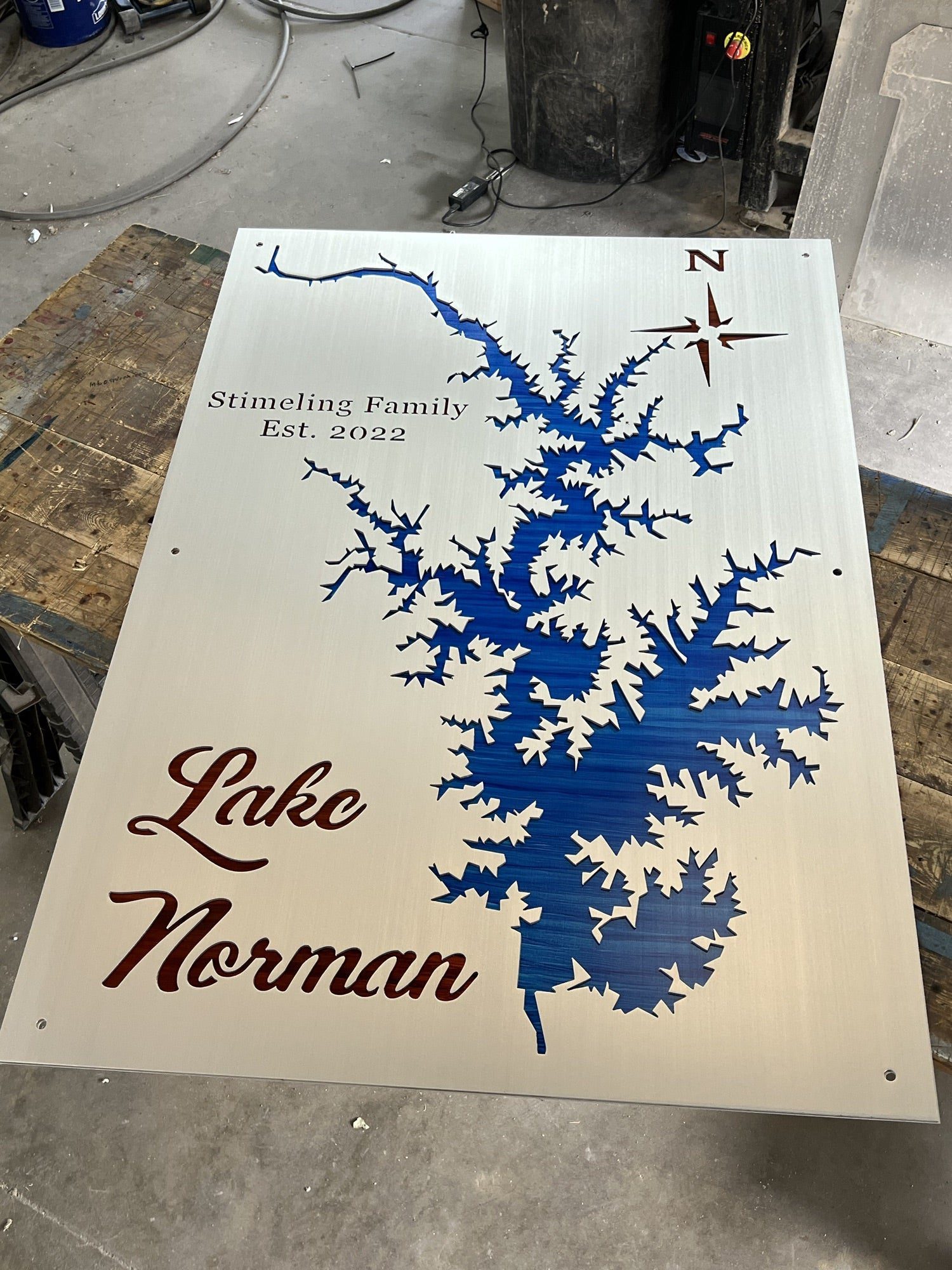 Lake Norman metal map with "Stimeling Family Est. 2022" text, featuring a compass rose on a wood surface.