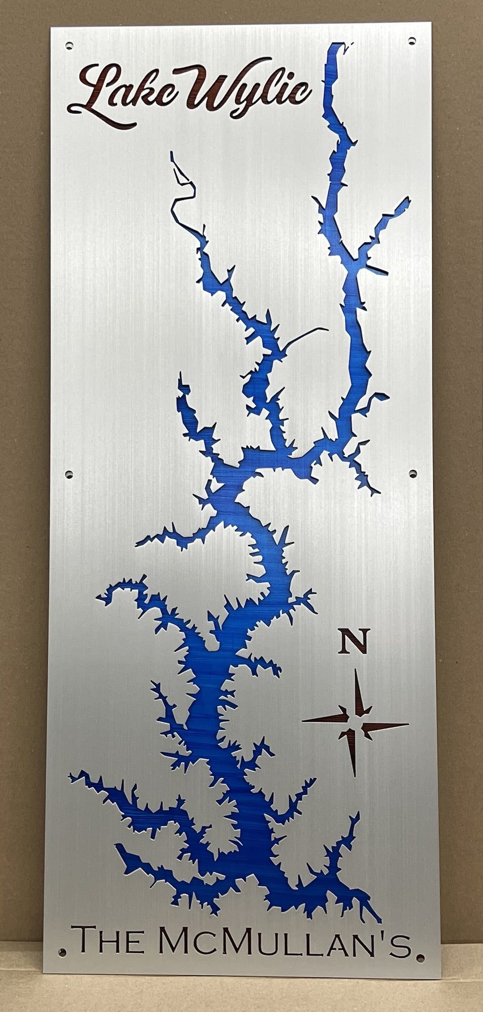 Lake Wylie metal map with blue cutout, compass rose, and "The McMullan's" text on brushed metal background.