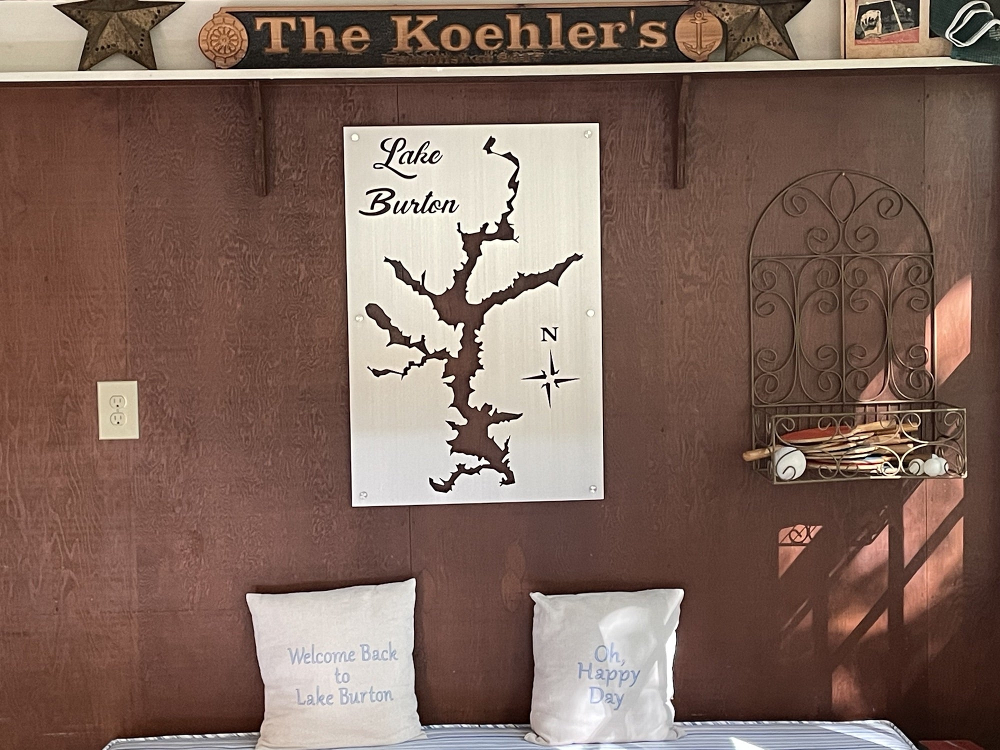 Lake Burton cutout on metal with compass rose, surrounded by decor and "The Koehler's" sign. Pillows say "Welcome Back."