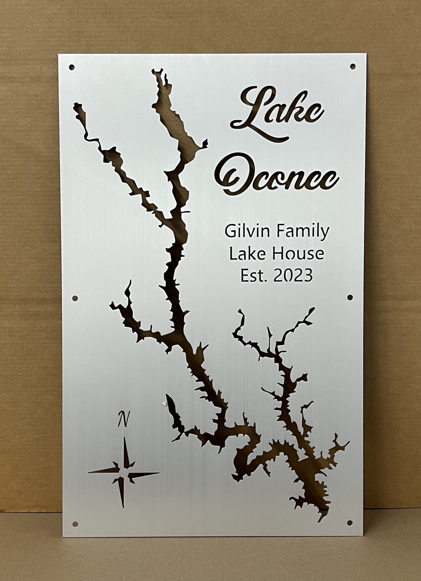 Lake Oconee map with "Gilvin Family Lake House Est. 2023" text and compass rose on brushed metal.