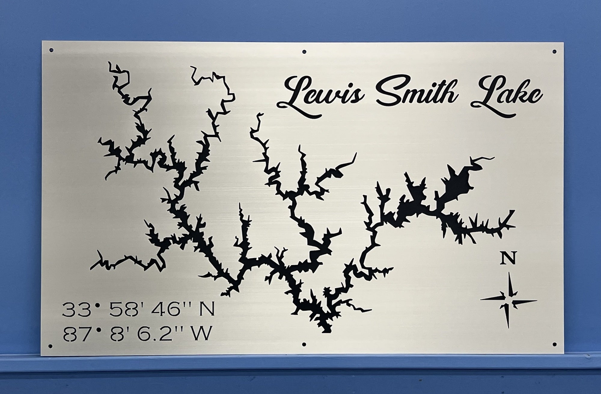 Lewis Smith Lake metal map with coordinates and compass rose, mounted on a blue wall.