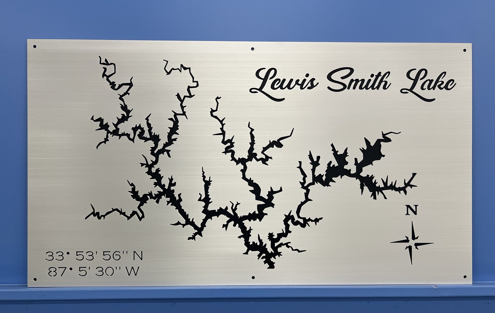 Lewis Smith Lake map with compass rose and coordinates, displayed on a brushed silver background against a blue wall.