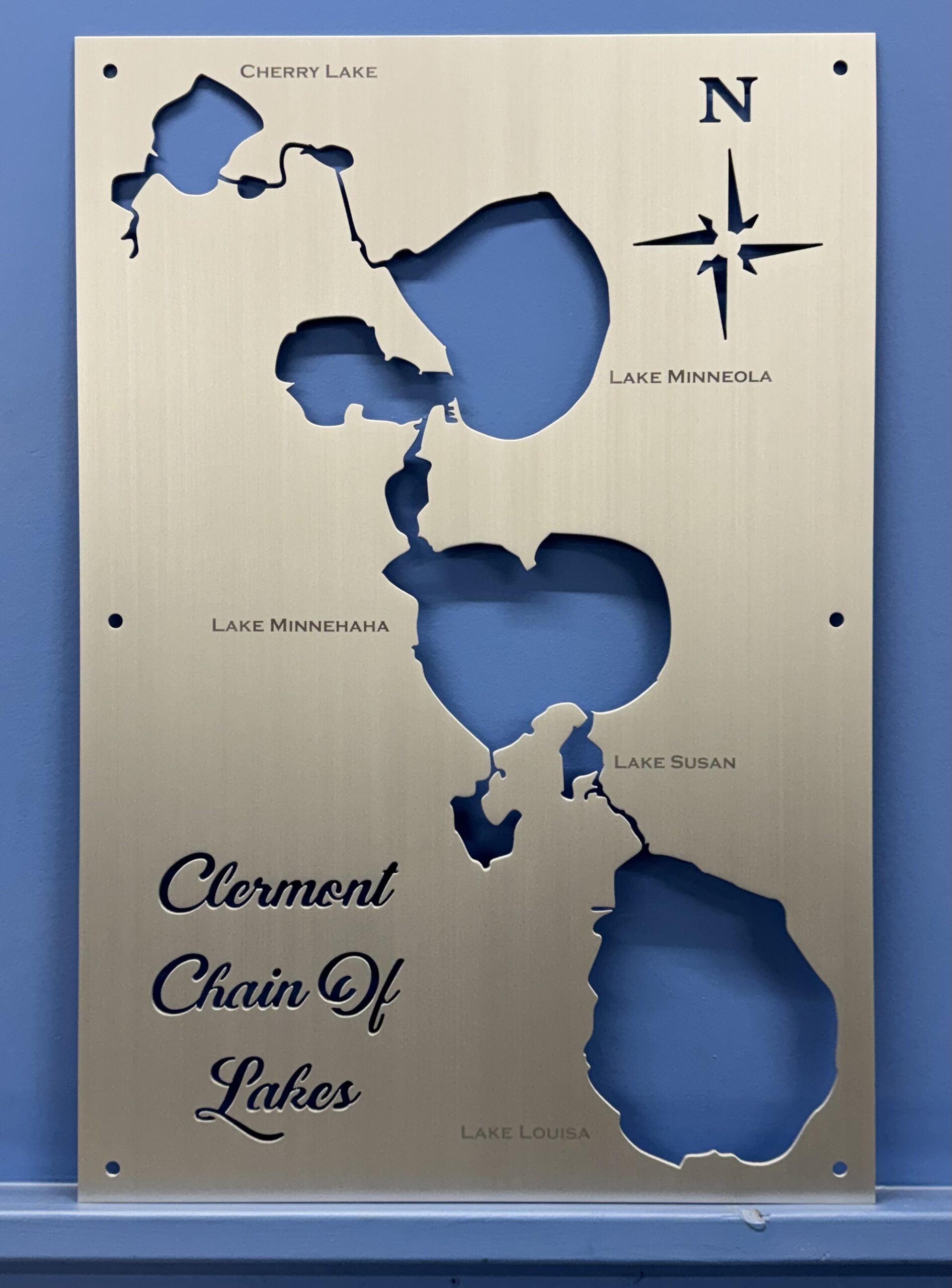Clermont chain of lakes map on a brushed-metal plaque with labeled cutouts of Cherry, Minneola, Minnehaha, Susan, and Louisa.
