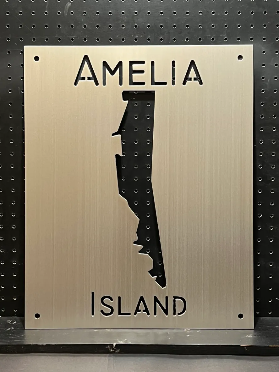 Metal sign features the words "Amelia Island" with a cutout map shape of the island.