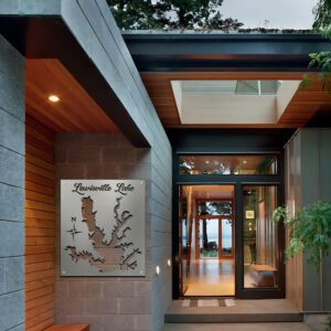 Modern entrance to a home featuring a Lewisville Lake sign, wooden accents, and large glass doors.