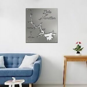 Metal map of Lake Hamilton displayed on a wall above a blue couch and wooden table with a plant.