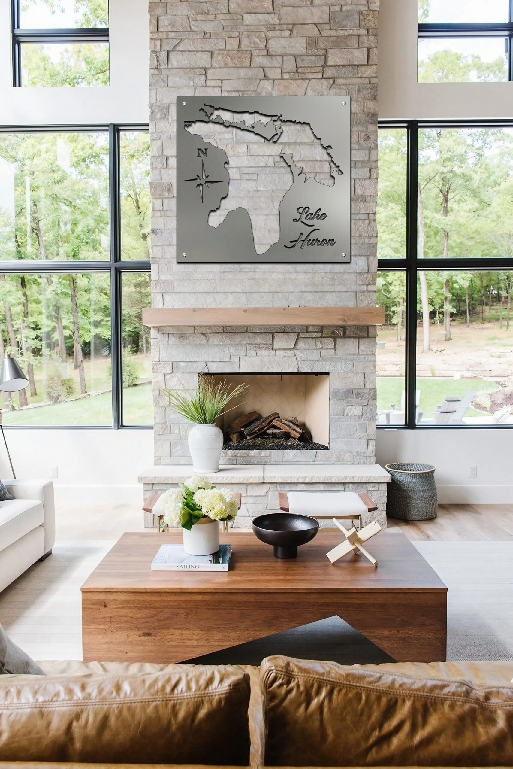 Metal map of Lake Huron hangs above a stone fireplace in a modern living room with large windows.
