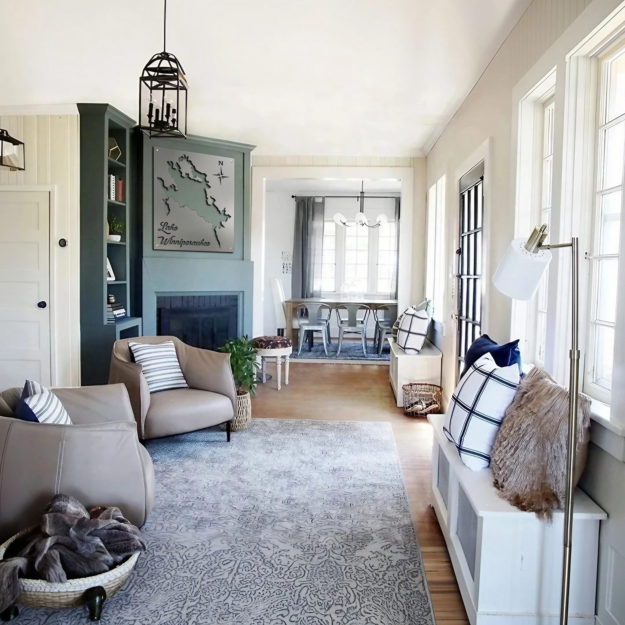 Living room featuring a metal map of Lake Winnipesaukee, cozy seating, and a dining area with large windows.