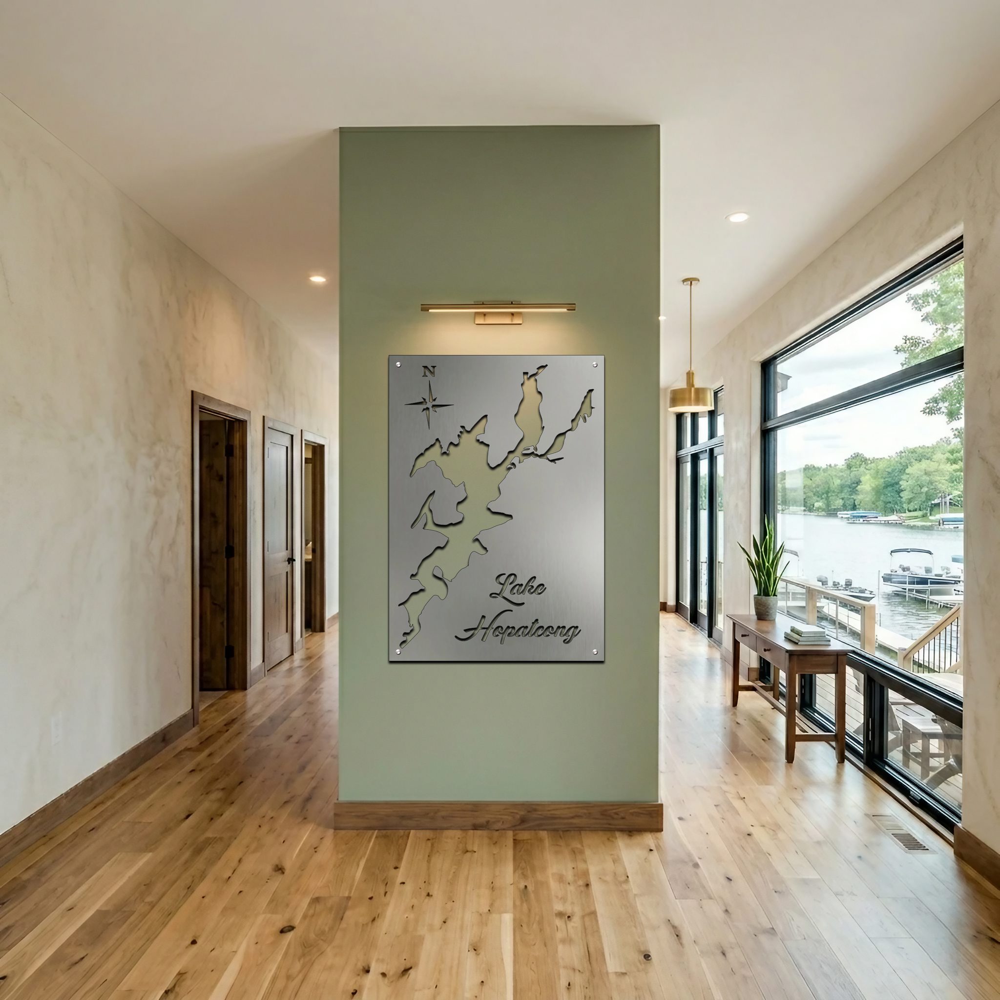 Metal map of Lake Hopatcong displayed on a green wall in a modern hallway. Natural light enters through large windows.