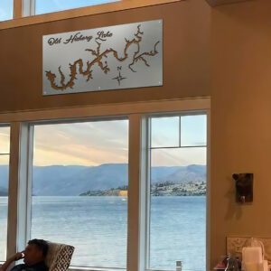 Metal map of Old Hickory Lake hangs above a person sitting in a chair, with scenic lake view through large windows.