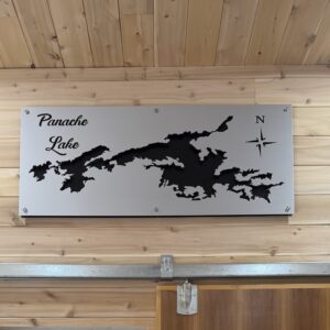Metal map of Panache Lake mounted on wooden wall, featuring lake outline and north compass rose.