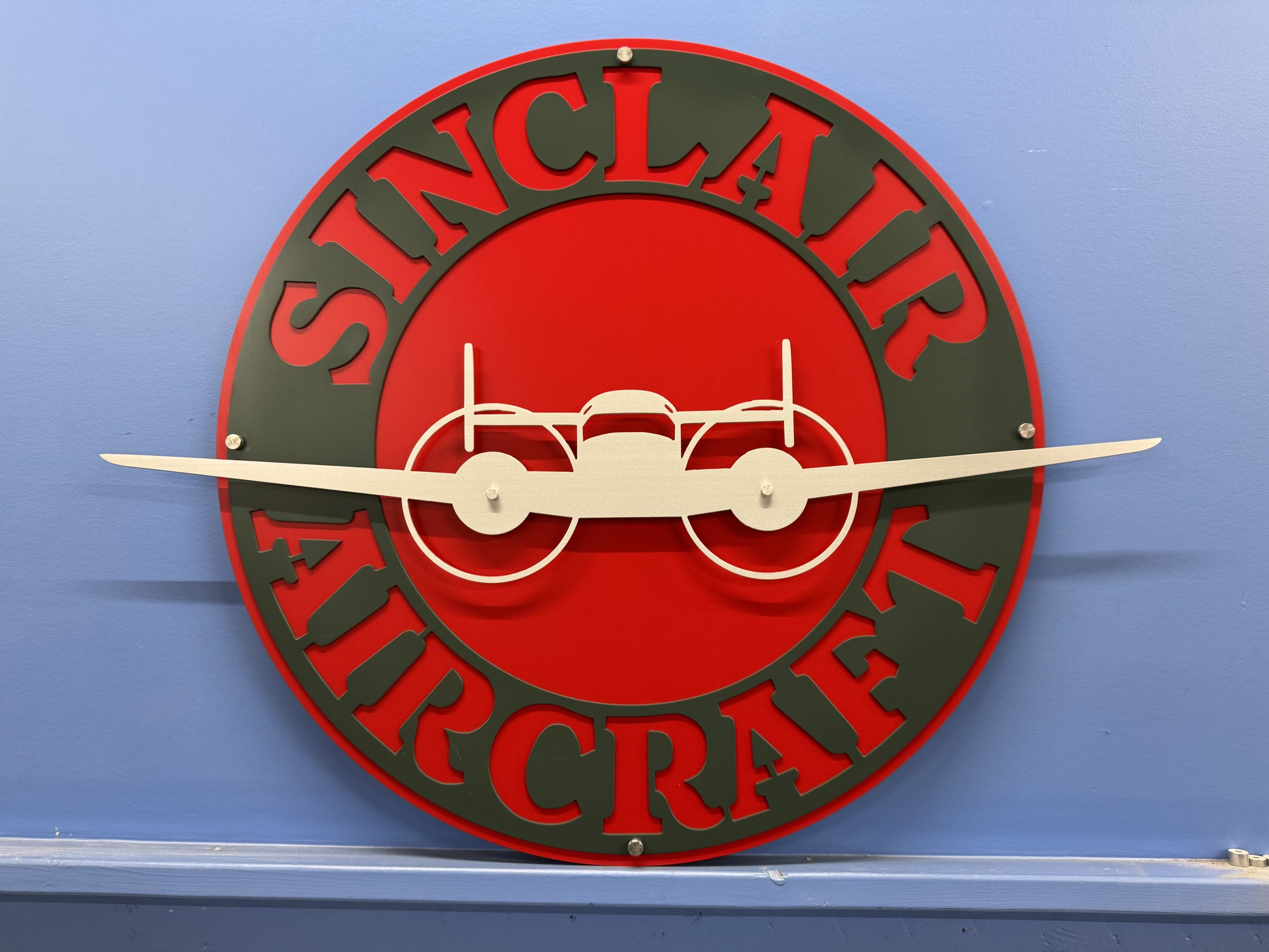 Custom multicolor Sinclair Aircraft metal sign with a raised airplane element.