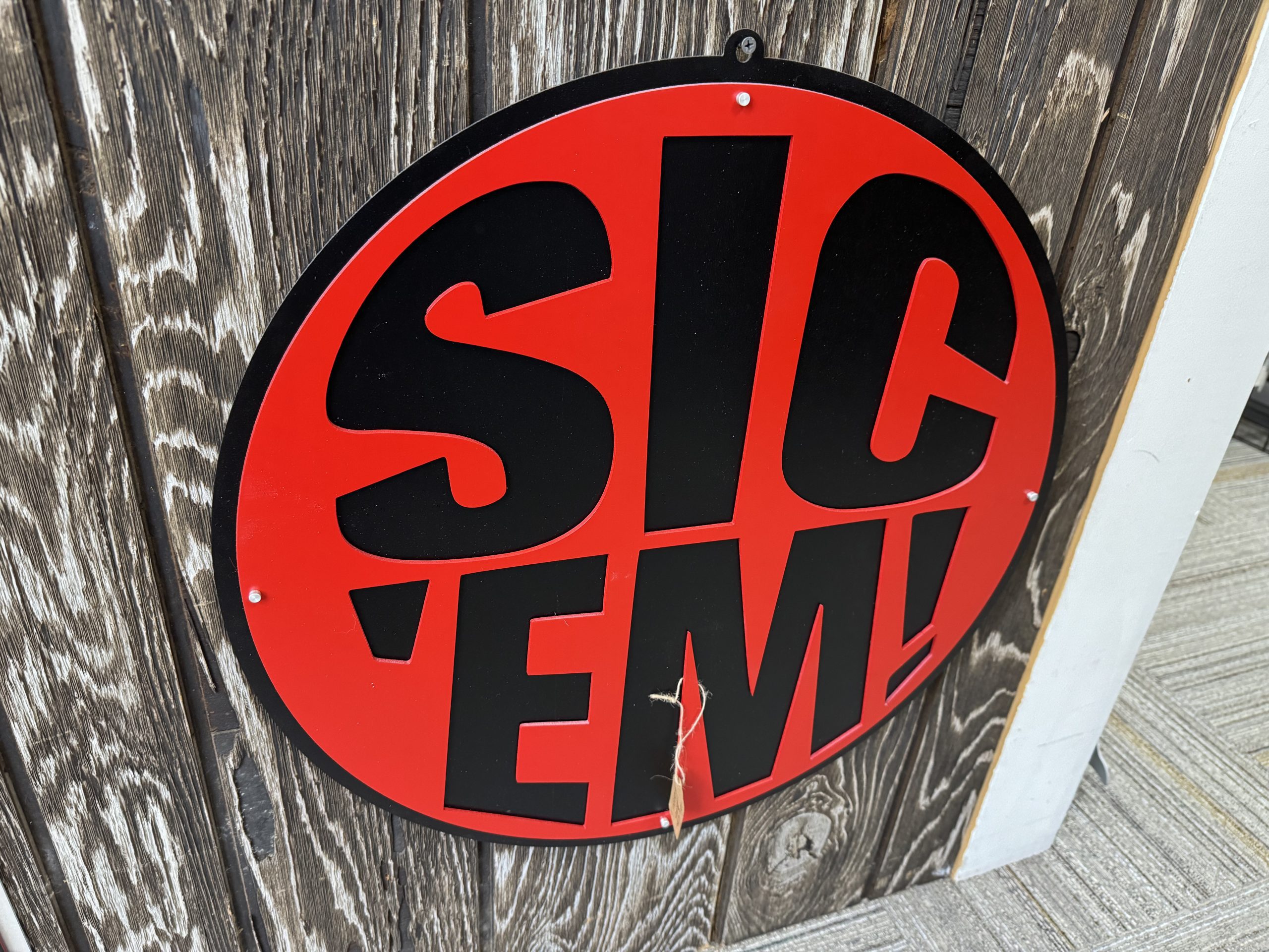 Custom red and black metal sign reading Sic Em, with a paw design.
