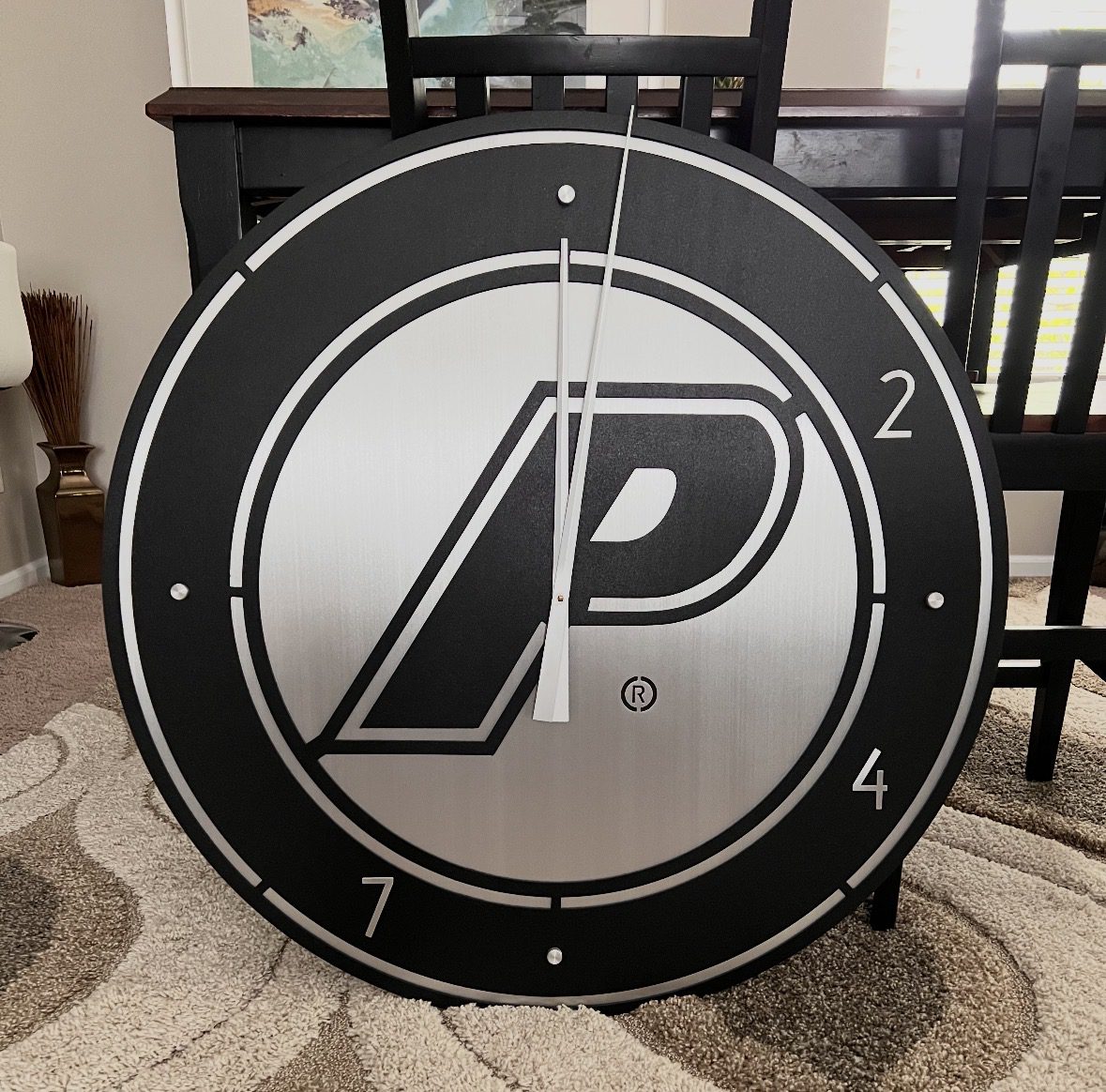 Custom round metal logo sign shown against a dark background.